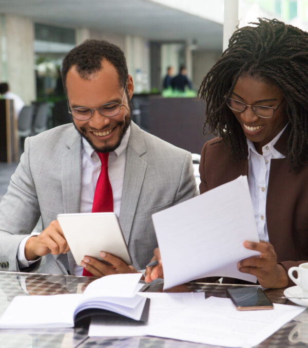 Cheerful business colleagues checking documents Cheerful business colleagues checking documents during coffee break. Business man and woman sitting in cafe, reading documents and using tablet. Paperwork concept